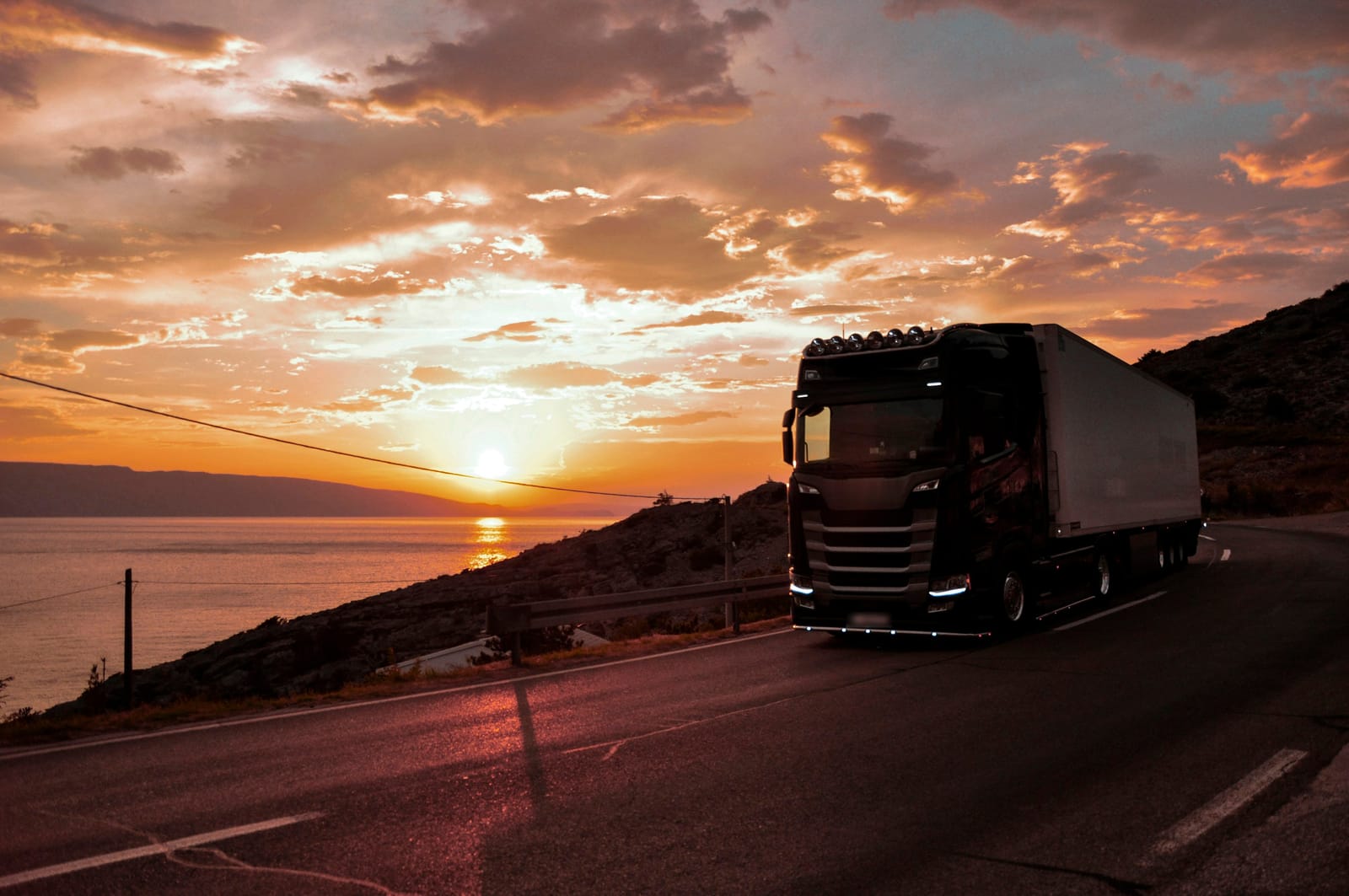 Truck on a coastal road at sunset